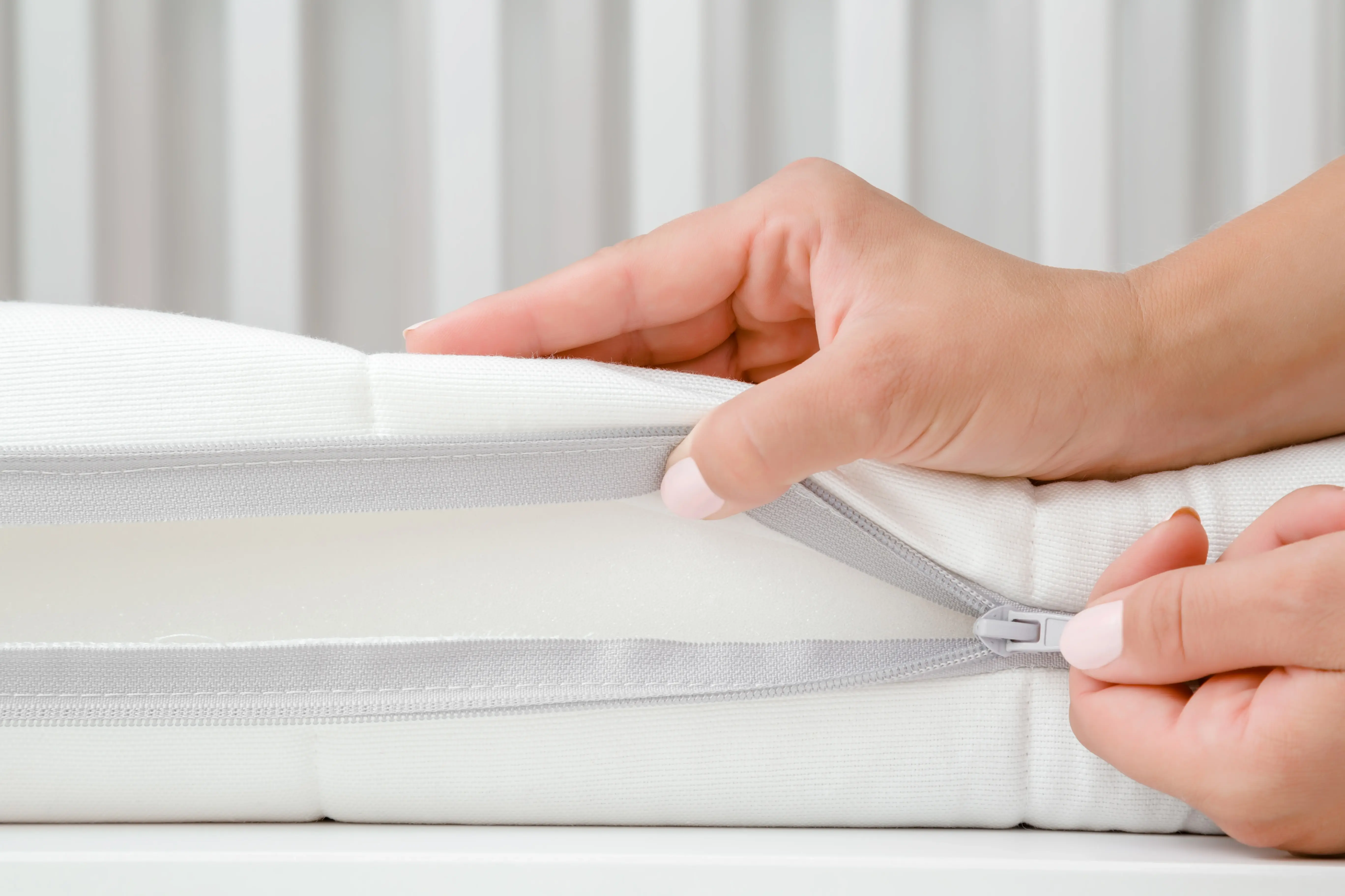 Abre a mano la cremallera de un topper: muestra la funda extraíble para facilitar su cuidado y protección.